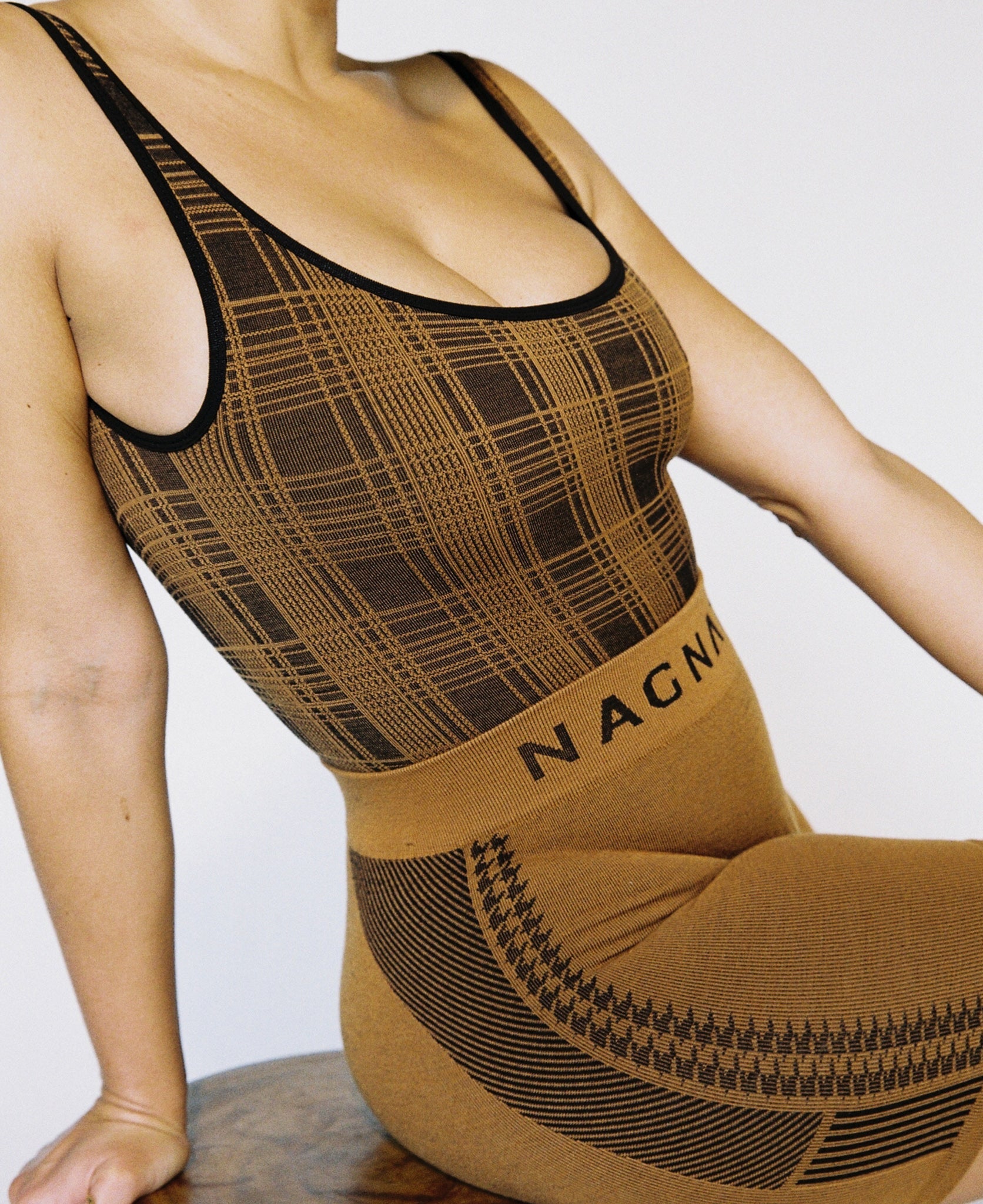 Female model wears the Nagnata Check-Back Bodysuit in black & bronze