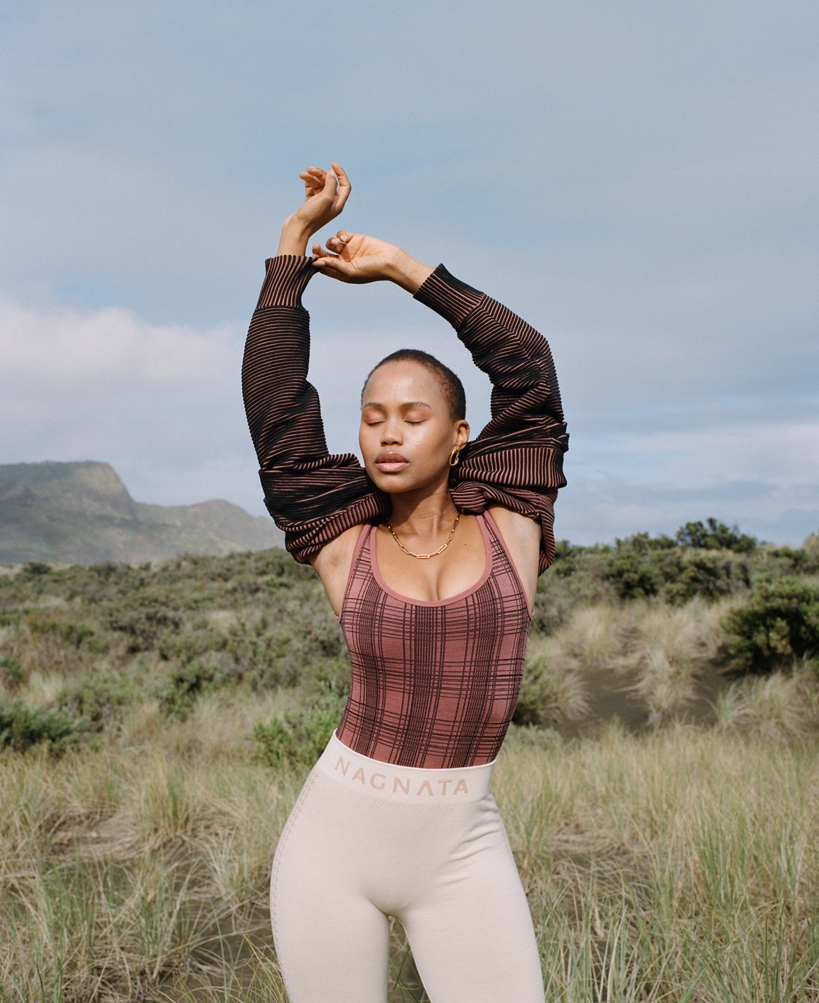 Female model wears the Nagnata Check-Back Bodysuit in blush & black