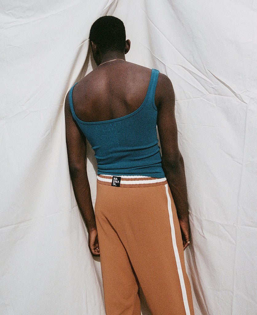 Female model wears the Nagnata Avika Tank in black and teal with the Yoni Short in Navy
