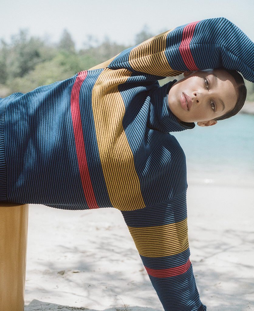 Female model wears the Nagnata Retro Rib Sweater in blue and turmeric