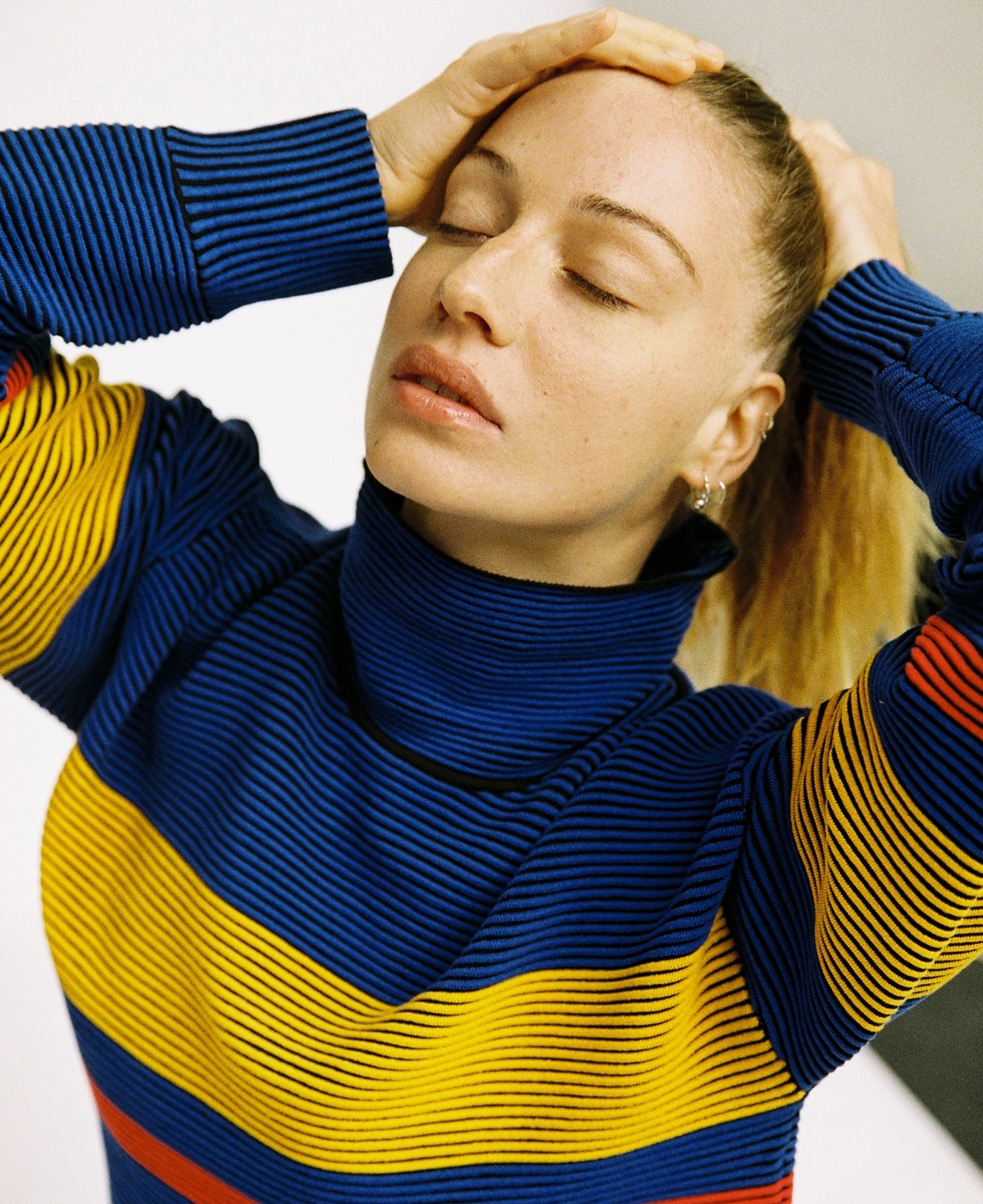 Female model wears the Nagnata Retro Rib Sweater in blue and turmeric