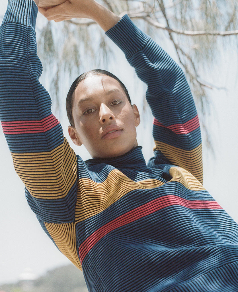 Female model wears the Nagnata Retro Rib Sweater in blue and turmeric