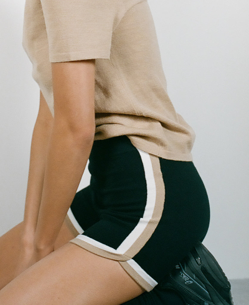 Female model wears the Nagnata Retro Short in black, cream and sandstone