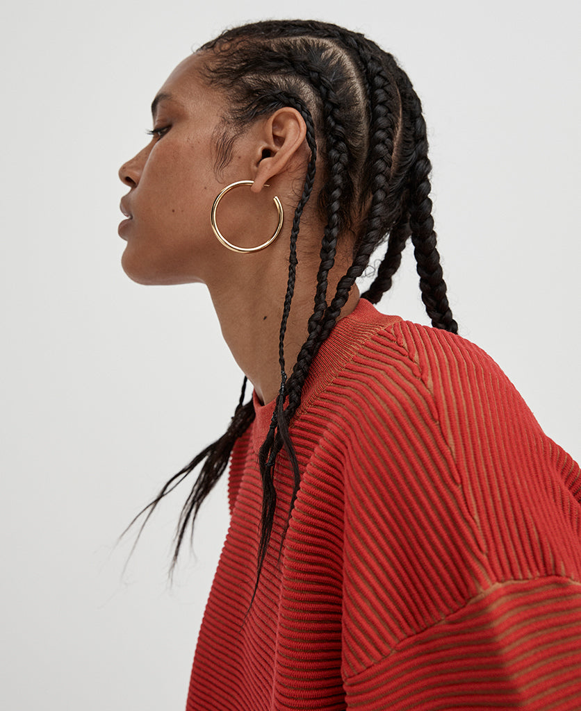Female model wears the Nagnata Sonny Crew Neck Sweater in red and bronze