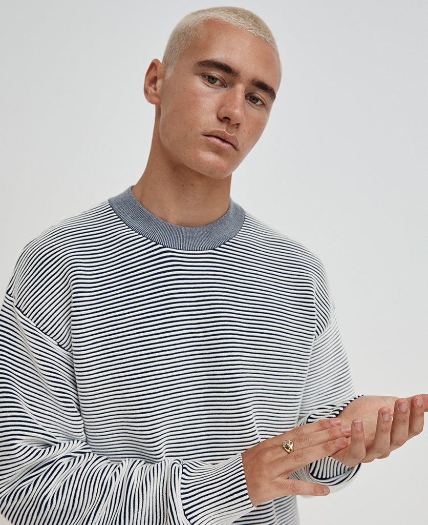 Male model wears the Nagnata Sonny Crew Neck Sweater in cream and navy