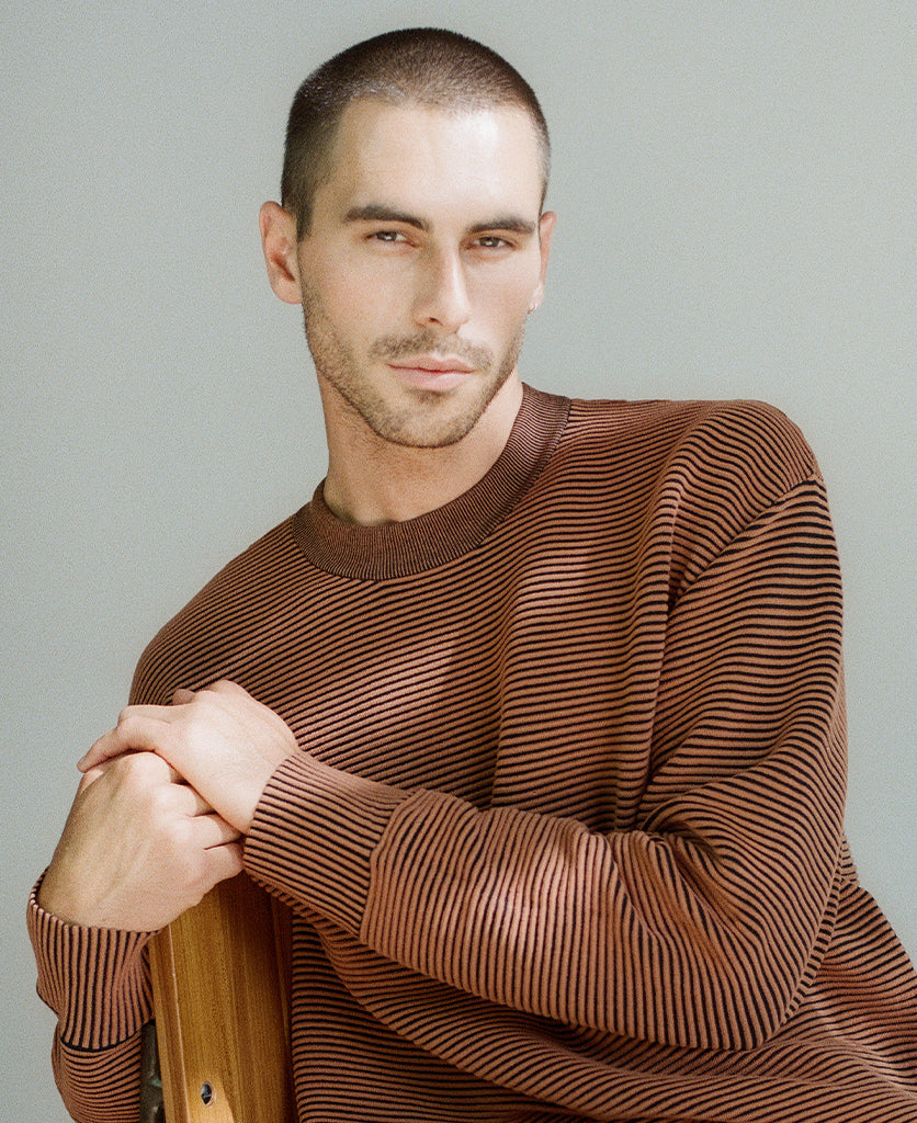 Male model wears the Nagnata Sonny Crew Neck Sweater in bronze and black