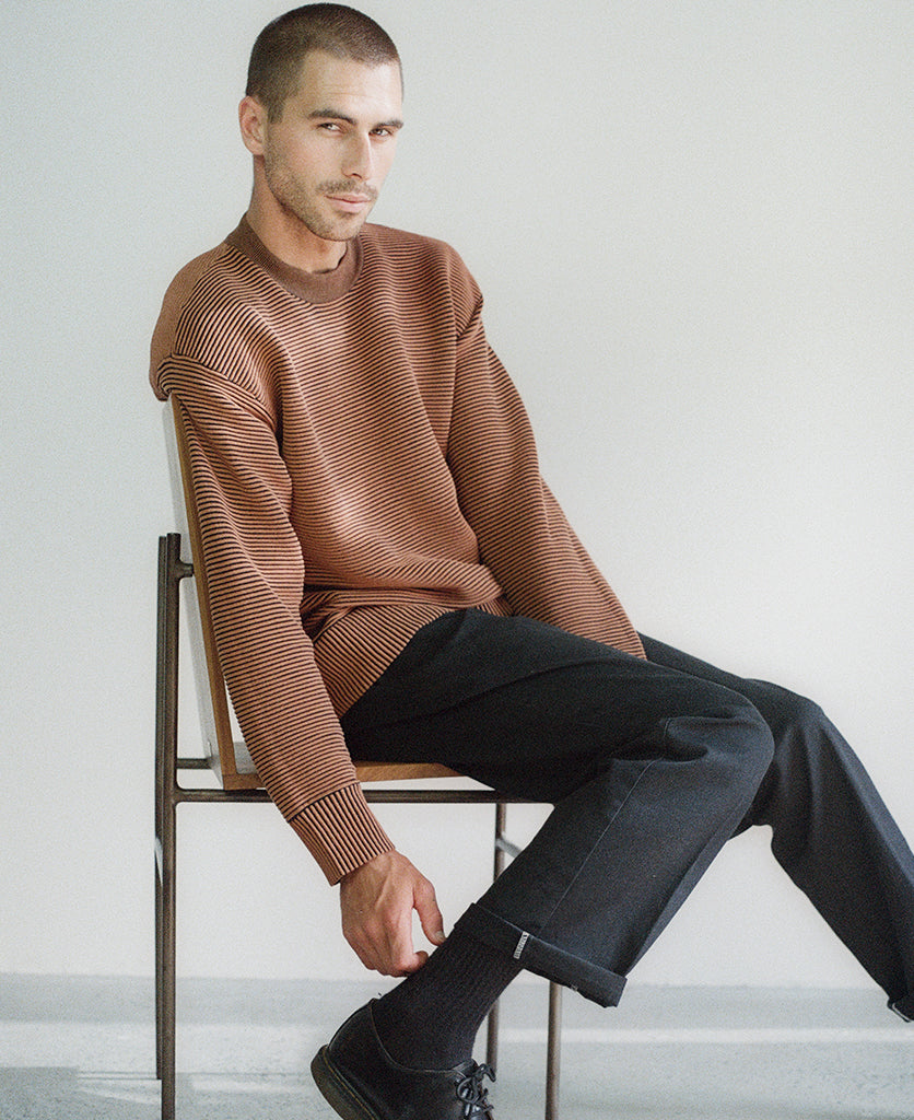 Male model wears the Nagnata Sonny Crew Neck Sweater in bronze and black