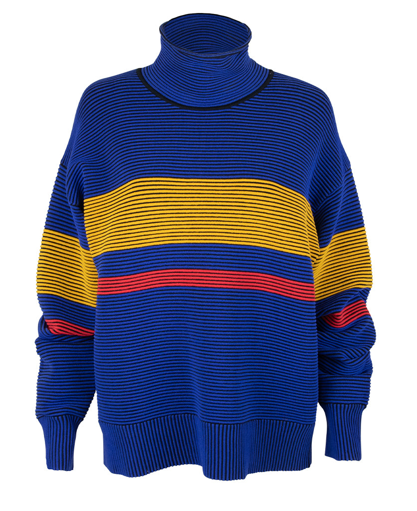 Female model wears the Nagnata Retro Rib Sweater in blue and turmeric