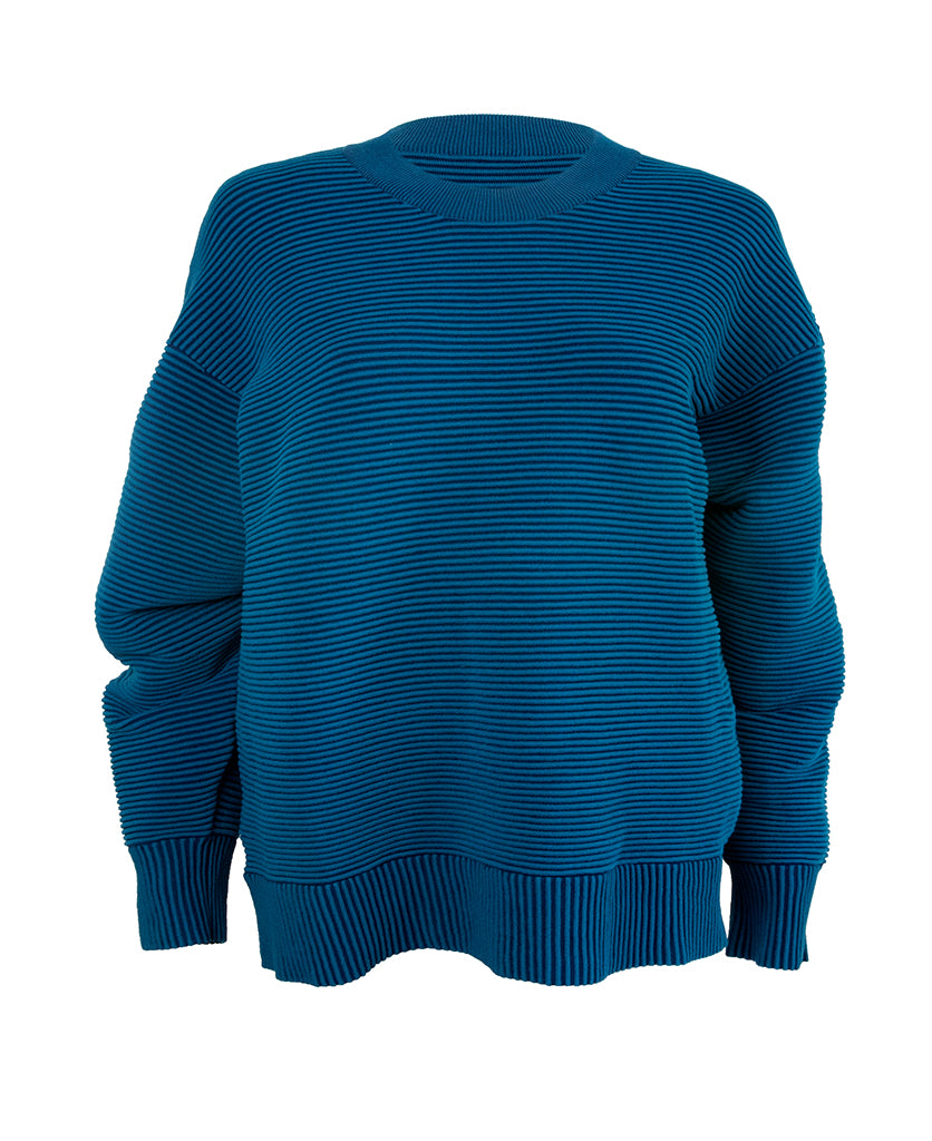 Female model wears the Nagnata Sonny Crew Neck Sweater in teal and navy