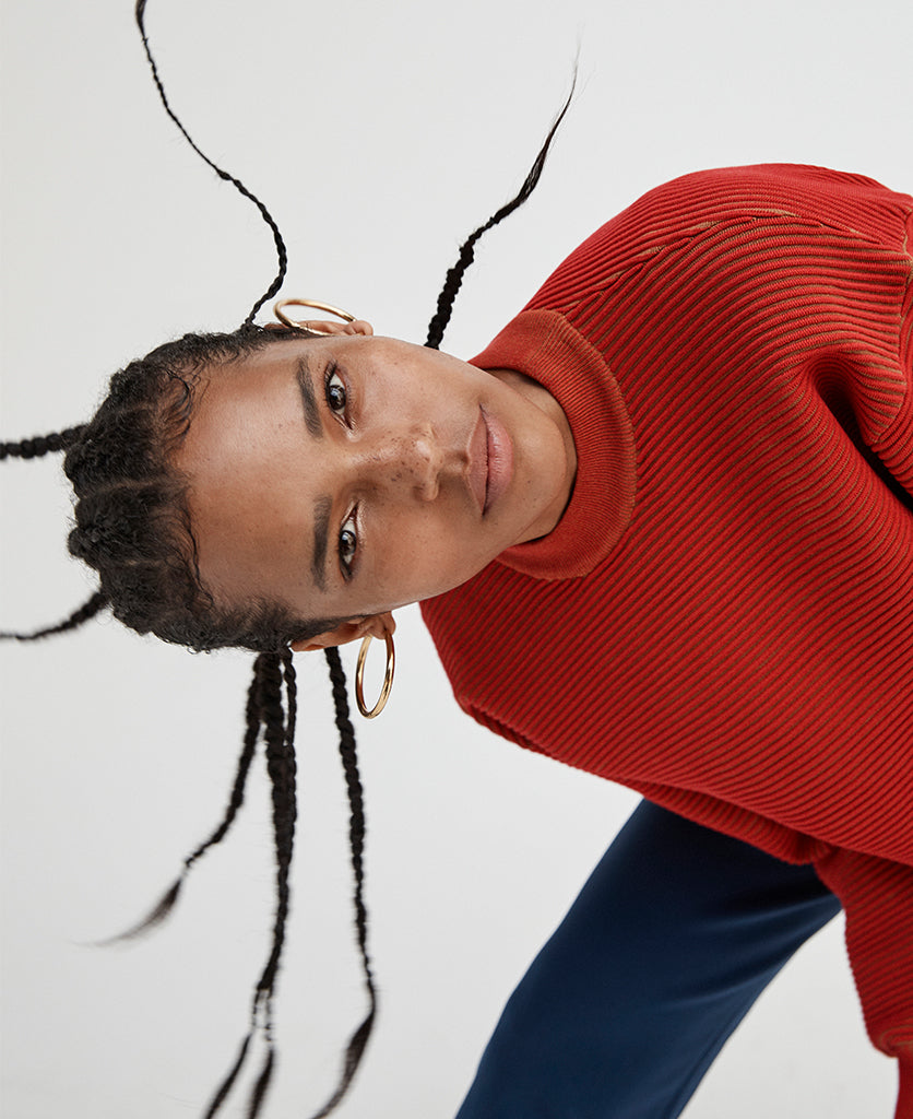 Female model wears the Nagnata Sonny Crew Neck Sweater in red and bronze